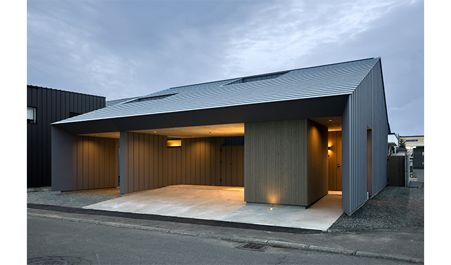 道路からの北側外観夕景。軒高を抑えた切妻屋根の2階建。13年前に建てた子世帯のコートハウスと並び建つ。