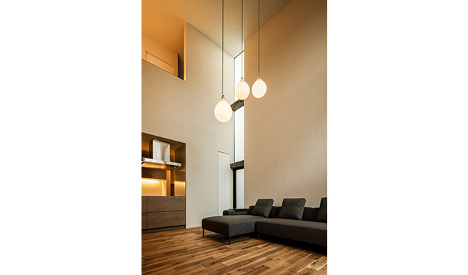 リビングは吹抜を介しゆるやかに2階とつながる。壁際に切った縦連窓からは東からの光が差し込む。