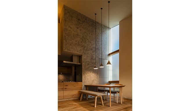 リビングからダイニングを望む。ダイニング脇にしつらえた床から天井迄のスリット窓からは南東からの光が差し込む。