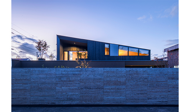 南東側外観夕景。2F屋上テラスは深い軒を持つ。