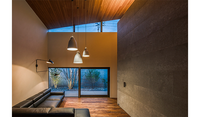 リビング夕景。テラス越しに植栽がライトアップされたメインコートとつながる。