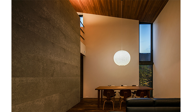 ダイニング夕景。チーク張りの天井がハーフウォール上の間接光で美しく浮かび上がる。
